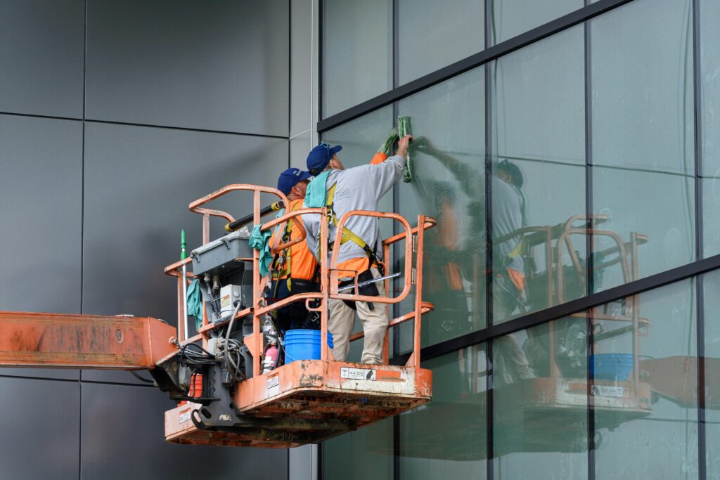 pexels-photo-31983867-31983867 Window cleaners working on a skyscraper using a hydraulic lift in urban setting.